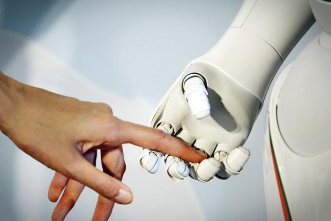 La mano di una donna è tenuta dalla mano di un robot.