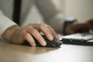 يد رجل أعمال تستخدم فأرة الكمبيوتر والكتابة ، شراكة أ