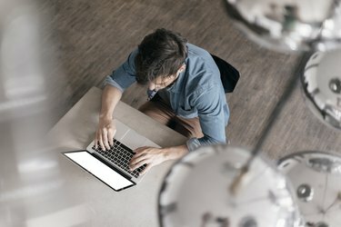 Junger Mann arbeitet am Laptop, Ansicht von oben