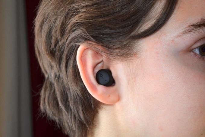 Bir kadın 1More ComfoBuds Mini kulaklık takıyor.
