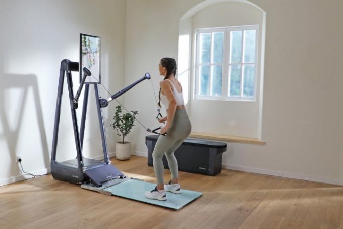 Uma mulher usando o Gymera Smart Home Gym em casa.