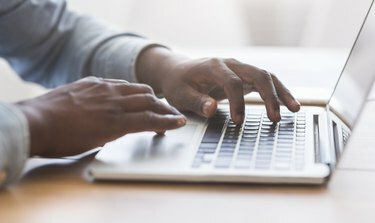 Onherkenbare Afro-Amerikaanse man die op het toetsenbord van de laptop typt op kantoor