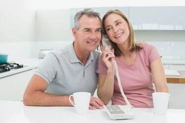 Счастливая пара, используя стационарный телефон вместе на кухне