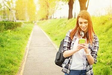 Szczęśliwa rudowłosa dziewczyna z liceum z SMS-em na smartfonie