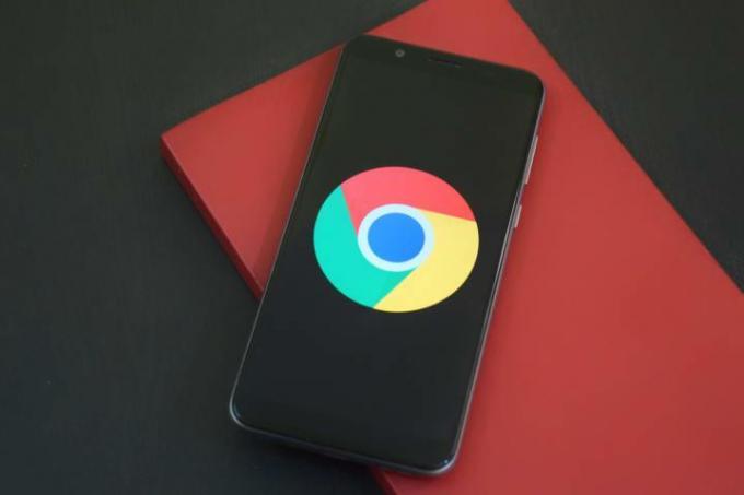 赤い本の上に置かれた黒い電話の Google Chrome ロゴ