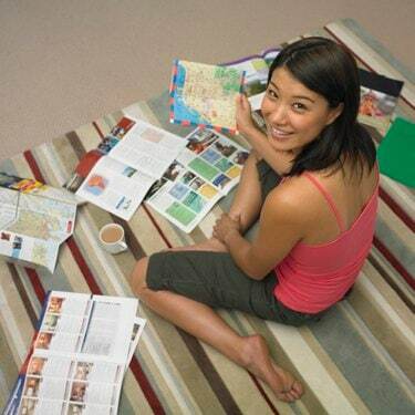Високий кут зору азіатської жінки, дивлячись на туристичні брошури