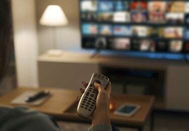 Jonge vrouw kijkt on-demand video op haar tv