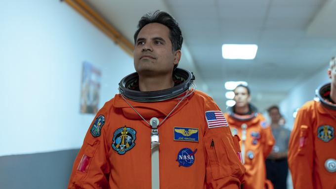 Michael Peña como José en traje espacial caminando por un pasillo en la película A Million Miles Away.