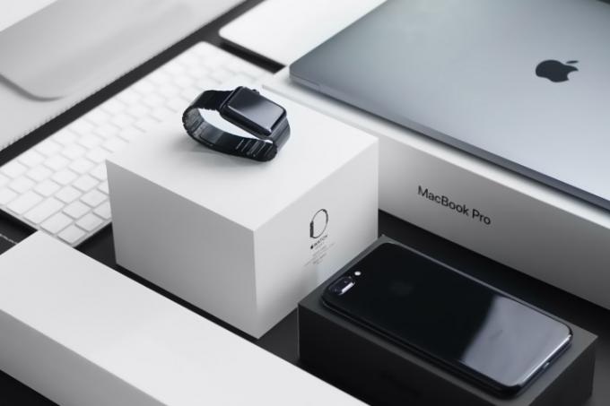 Et Apple Watch, iPhone og Macbook Pro sidder på et skrivebord.