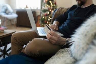 Hombre joven con tarjeta de crédito compras navideñas online en portátil
