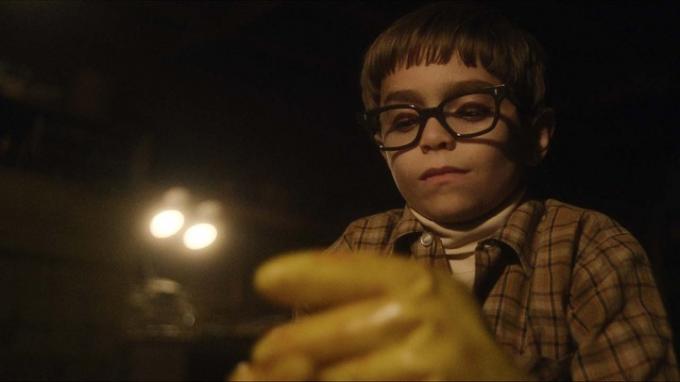 Un joven Jeffrey Dahmer con guantes en una escena de Monster: The Jeffrey Dahmer Story.