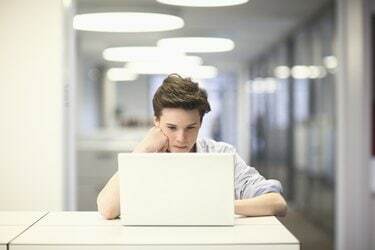 Tonårspojke som använder bärbar dator på kontoret