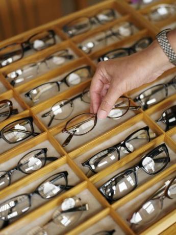 Mand vælger et par briller fra montre i butikken, nærbillede af hånden