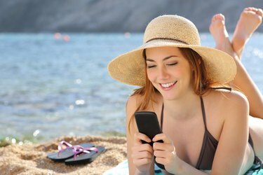 Ženska na plaži poleti pošilja sporočila pametnemu telefonu