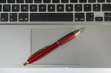 Химикалка, лежаща върху лаптоп