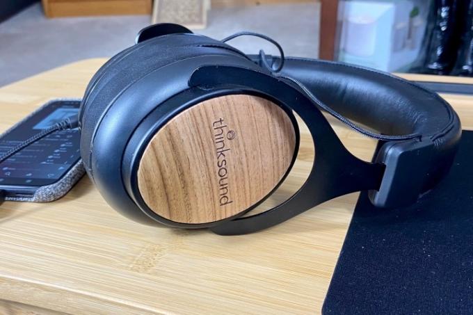 Los auriculares con cable Thinksound OV21 sobre una mesa junto a un teléfono.