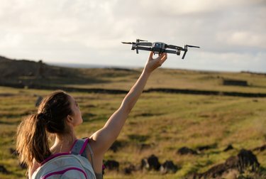 Foto di una ragazza in un grande campo che lancia in aria il drone Mavic Pro di DJI.