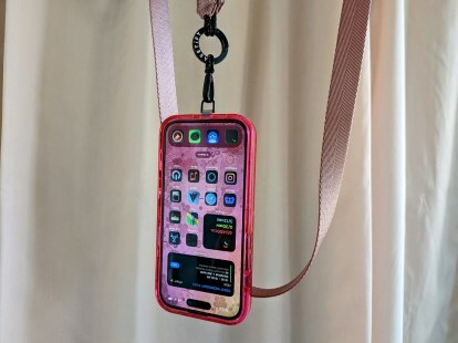 Casetify'ın Utility Crossbody İpi kayışına asılı bir iPhone 14 Pro.