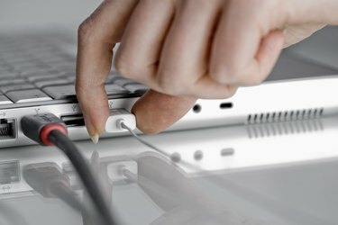 Hand mit Laptop-Computer mit USB-Kabeln