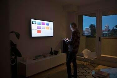 Vanhempi mies käyttää älytelevisiosovelluksia digitaalisella tabletilla pimeässä olohuoneessa