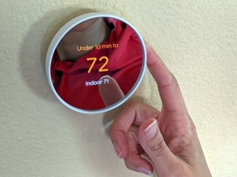 Asmuo, valdantis „Google Nest“ termostatą.