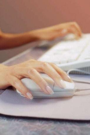 يد أنثى باستخدام فأرة الكمبيوتر ولوحة المفاتيح