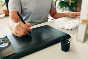 Γραφίστας που χρησιμοποιεί ψηφιακό tablet και υπολογιστή στο γραφείο