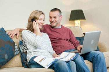 Casal maturo usando laptop, sentado no sofá