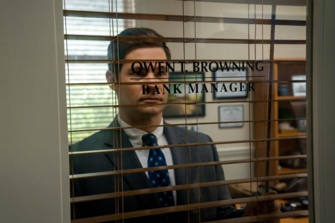 Adamas Devine'as žiūri pro savo banko biuro langą „The Out-Laws“.