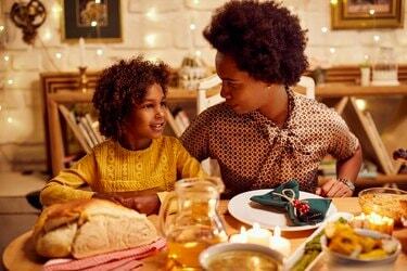ダイニングテーブルで感謝祭のランチをしながら話している笑顔の女の子と彼女の母親。