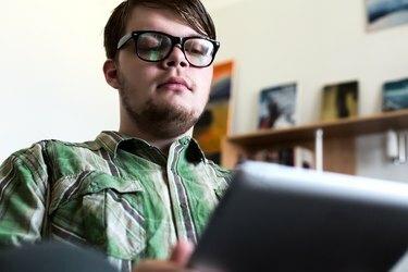 家のインテリアでタブレットコンピューターを使用して若い男の肖像画