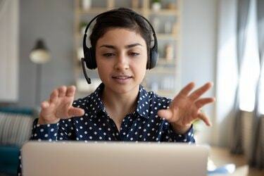 Indisk kvindelig lærer bærer trådløse headset-videoopkald på bærbar computer