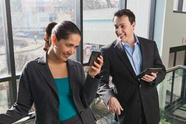 Cuplu de afaceri în birou uitându-se la tabletă și smartphone
