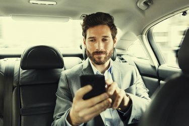 Homem moderno no carro digitando mensagem de texto no celular