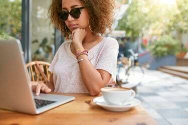 Vrouw bij café op de stoep die e-mails leest