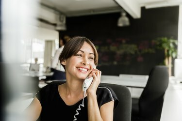 Fröhliche Geschäftsfrau mit Telefon im Büro