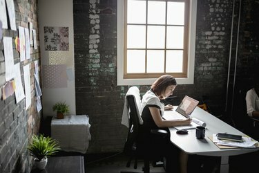 Mulher de negócios criativa dedicada trabalhando em um laptop no escritório