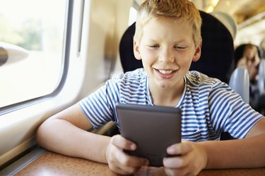 電車の旅で電子書籍を読んでいる少年