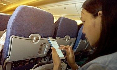vista lateral, de, adulto medio, mujer, utilizar, teléfono móvil, mientras, sentado, en, avión