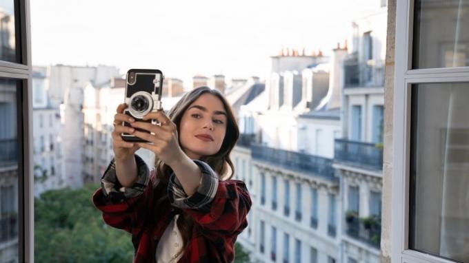 Emily fotografuojasi iš balkono Paryžiuje seriale Emily in Paris.