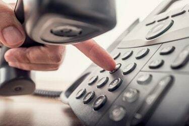 Close da mão masculina segurando o receptor do telefone enquanto disca um