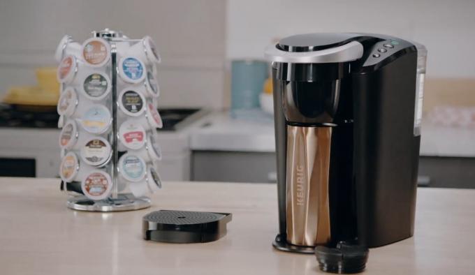 Keurig K-Compact kavos virimo aparatas kartu su kavos puodeliais.