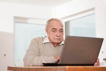 Starejši moški uporablja prenosni računalnik za mizo
