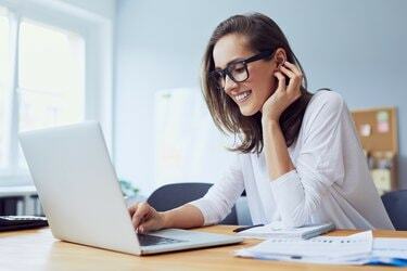 Portrét krásnej veselej mladej podnikateľky, ktorá pracuje na notebooku a smeje sa v domácej kancelárii