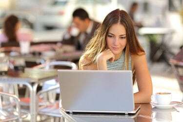 Mulher assistindo mídia em um laptop em uma cafeteria