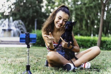 Tizenéves lány vlog bejegyzést csinál a parkban a kutyájával.