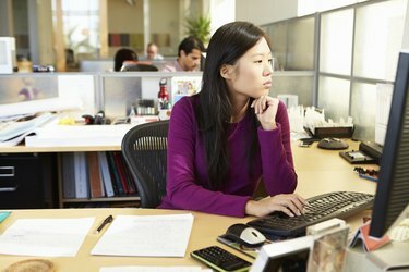 Donna asiatica che lavora al computer in un ufficio moderno