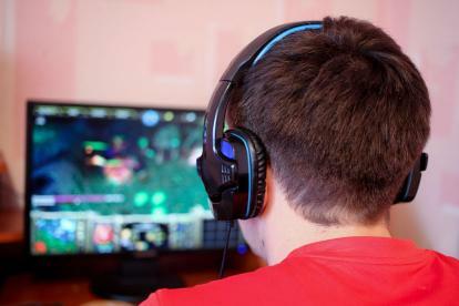 Homem usando fones de ouvido e olhando para o monitor.