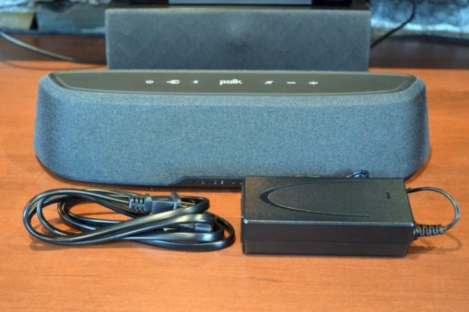 Soundbar Polk MagniFi Mini AX s externím napájecím zdrojem a AC kabelem.