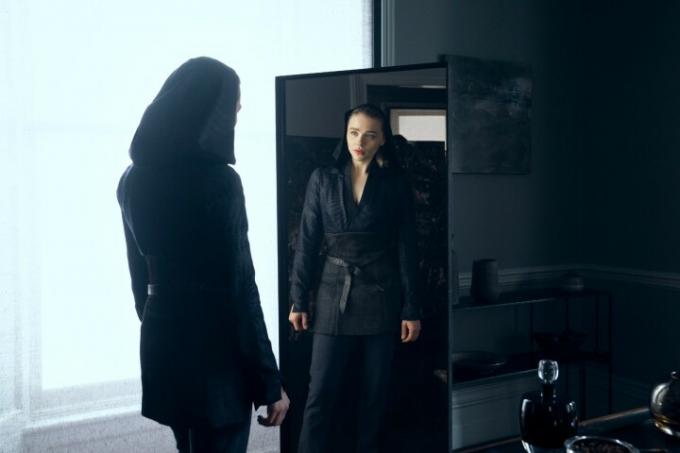 Chloe Grace Moretz se mira fijamente en un espejo en una escena de The Peripheral.